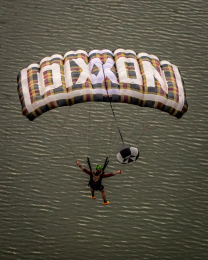 A jumper descends under a custom branded canopy at a 22 Jumps event